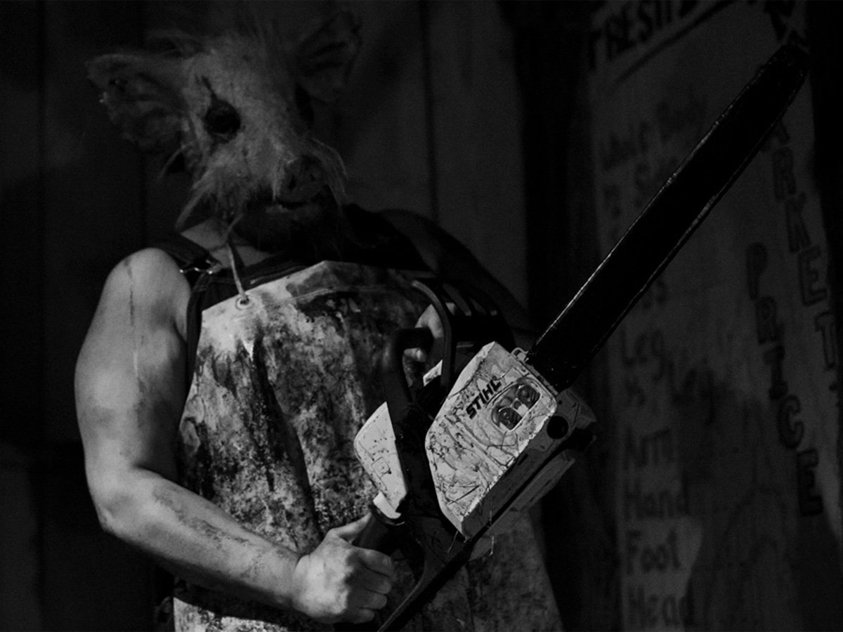 A blood-spattered butcher in a pig mask wielding a chainsaw on the Haunted Hayride