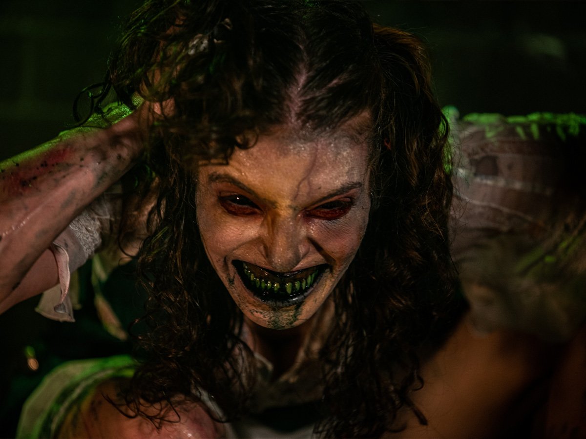 A snarling green-toothed creature in the dark at RISE Haunted House